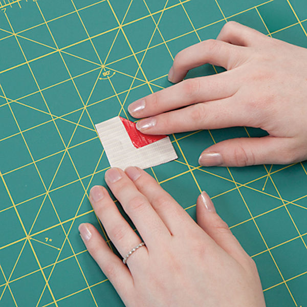 one corner of a square of Duck Tape folded to reach the center of the square